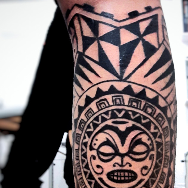 Tatuaje maorí con sol y tortuga rodeando la pierna