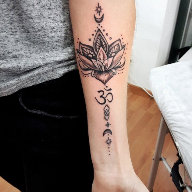 Tatuaje en antebrazo de mujer de flor de loto y Om