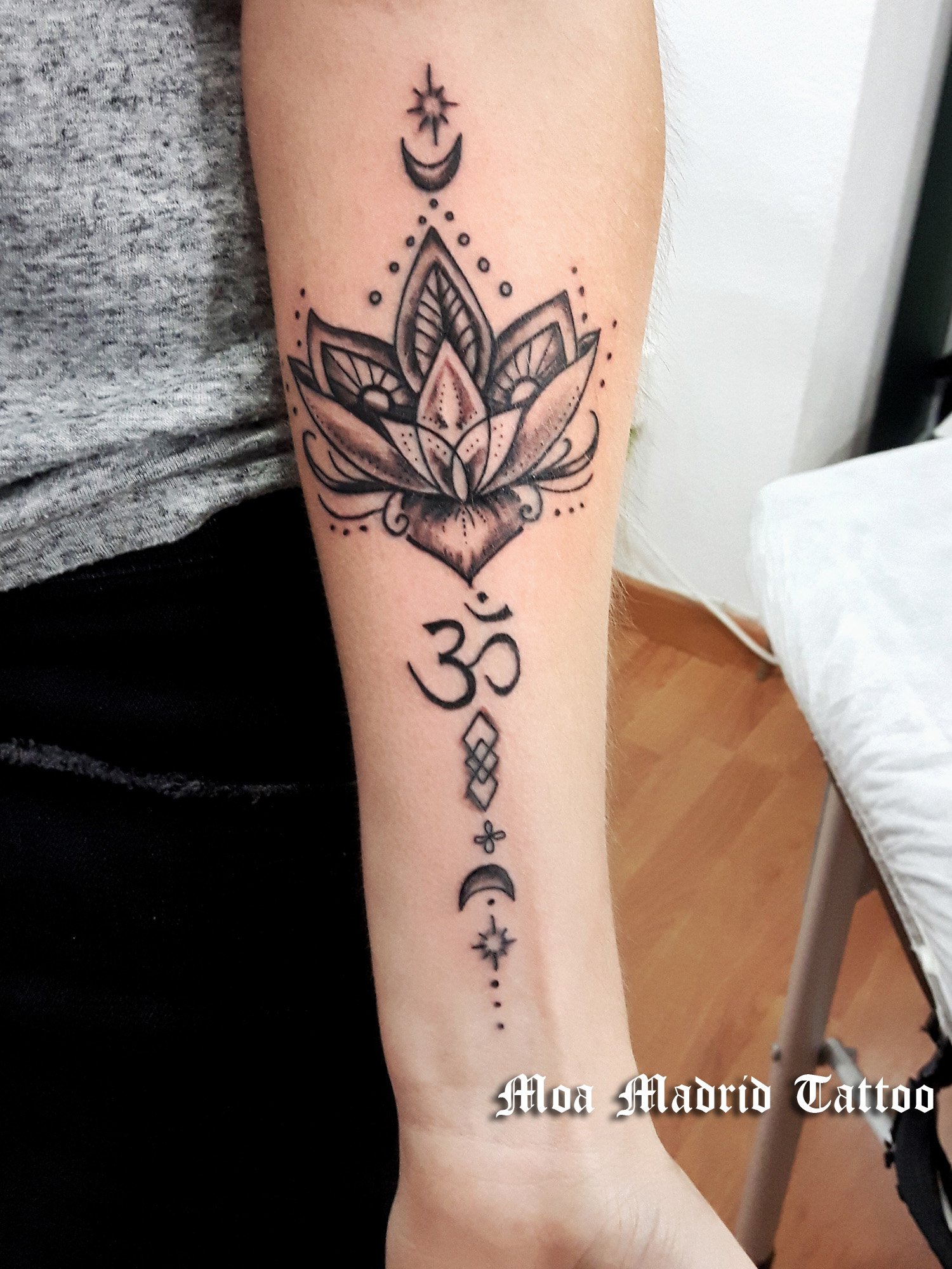 Tatuaje en antebrazo de mujer de flor de loto y Om