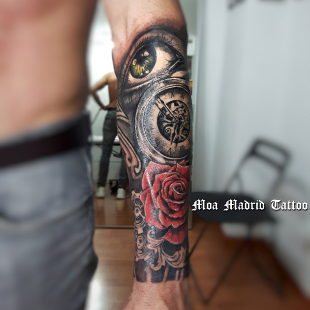 Tatuaje con ojo, reloj y rosa roja en el antebrazo