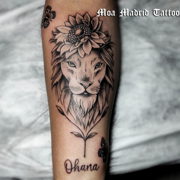 Tatuaje con león, flor y mariposas en antebrazo de mujer