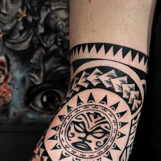 Tatuaje maorí con sol rodeando el codo