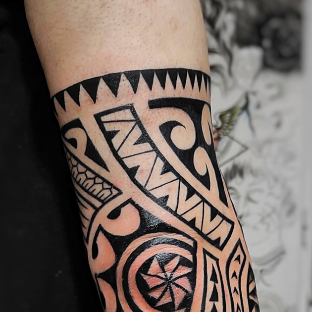 Tatuaje con sol maorí rodeando la zona del codo