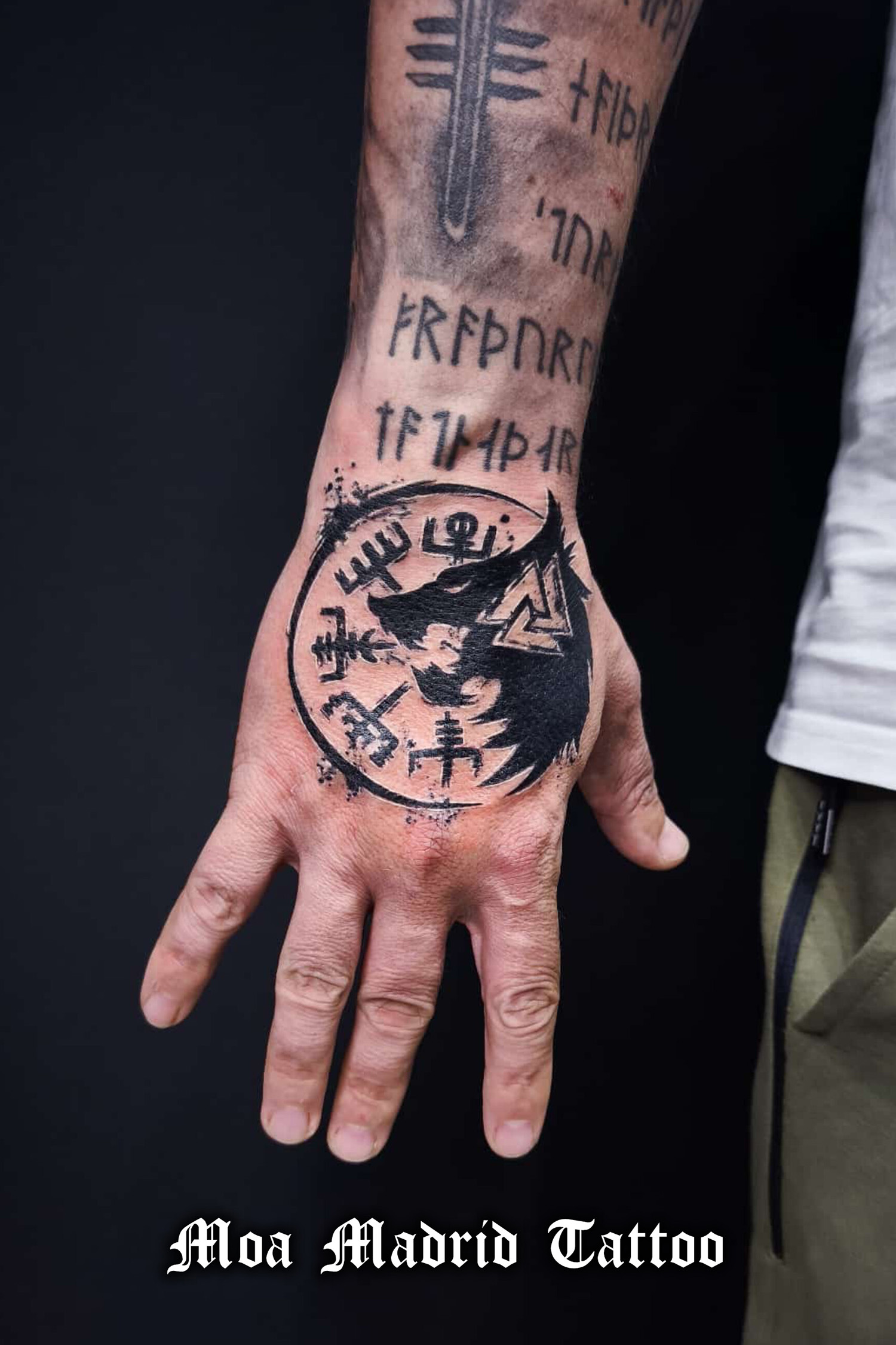 Tatuaje moderno de vegvísir y lobo en el dorso de la mano